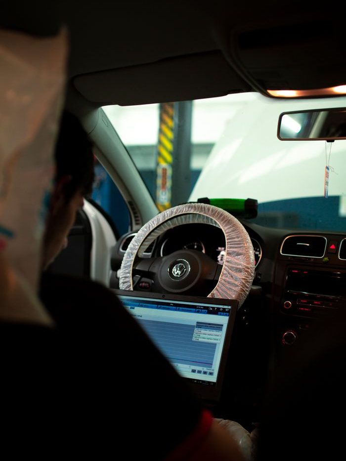 Mechanic inside car using laptop for diagnostics. Ideal for automotive and technology themes.