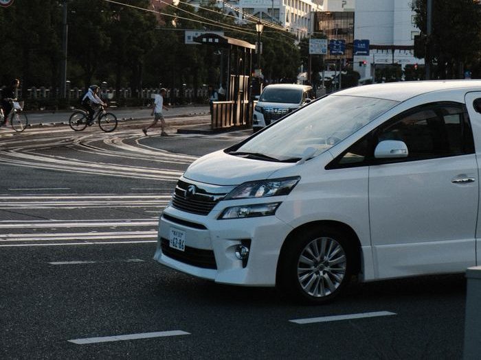 Busy street with cars and cyclists under electric wires during dusk in an urban area.