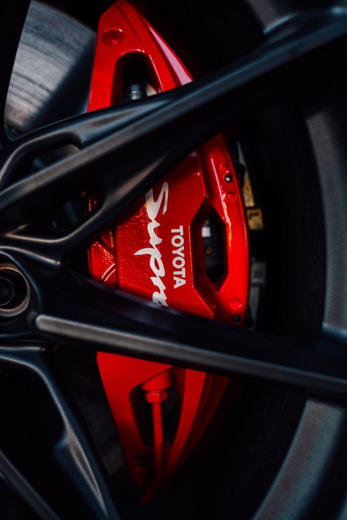 Detailed view of a red Toyota Supra brake caliper and wheel rim highlighting automotive design.